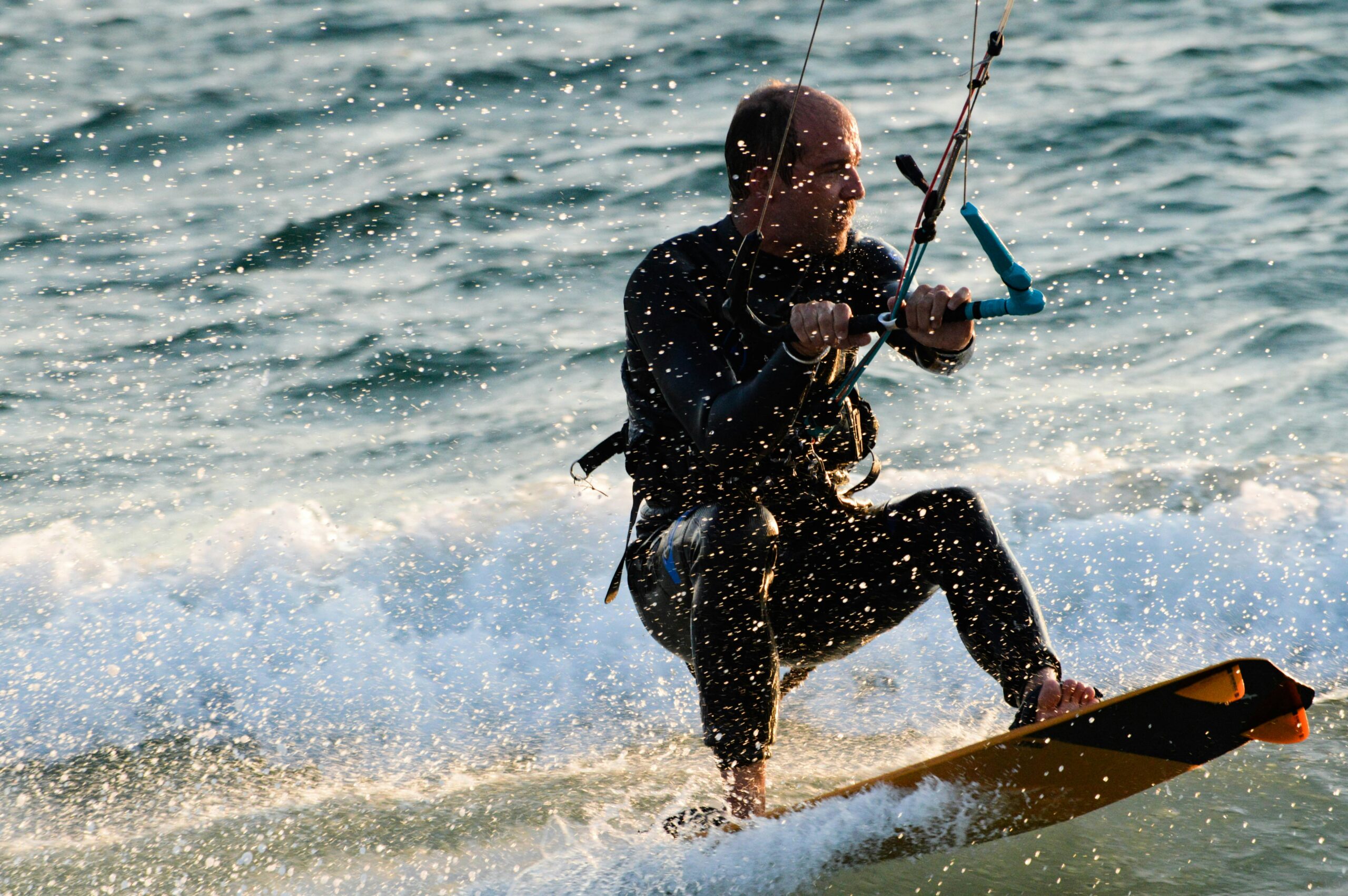 man in black wet suit riding on orange surfboard during daytime