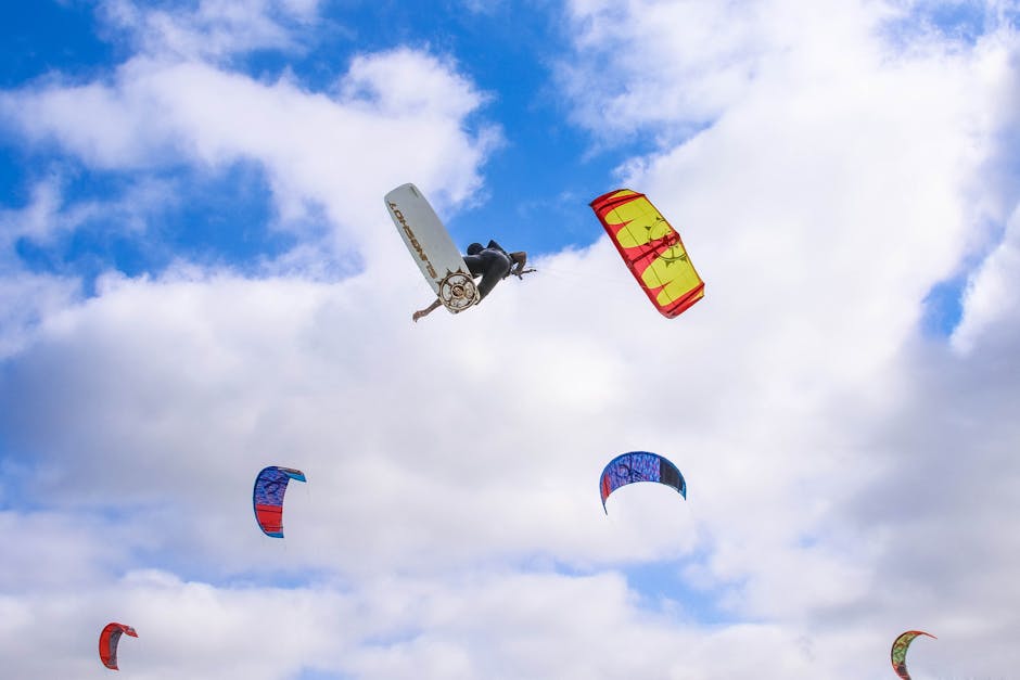 A dynamic scene of kitesurfing with colorful parachutes soaring through a cloudy sky.