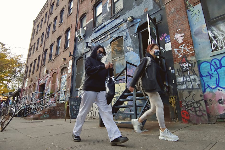 People walking past a graffiti-covered building in Brooklyn, New York.
