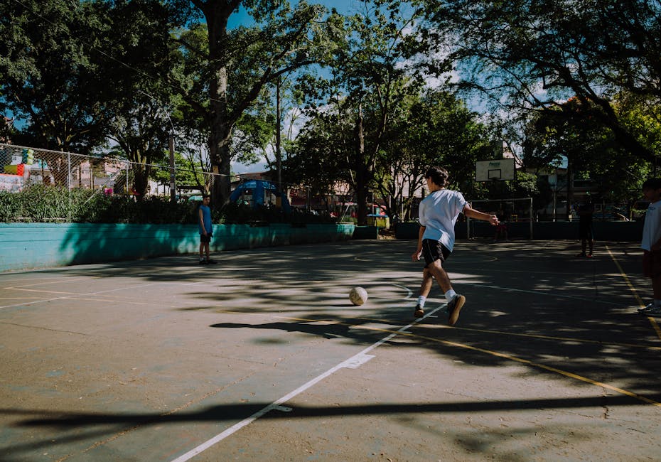 Boys play a casual game of football in a sunlit park in Medellín, Colombia.