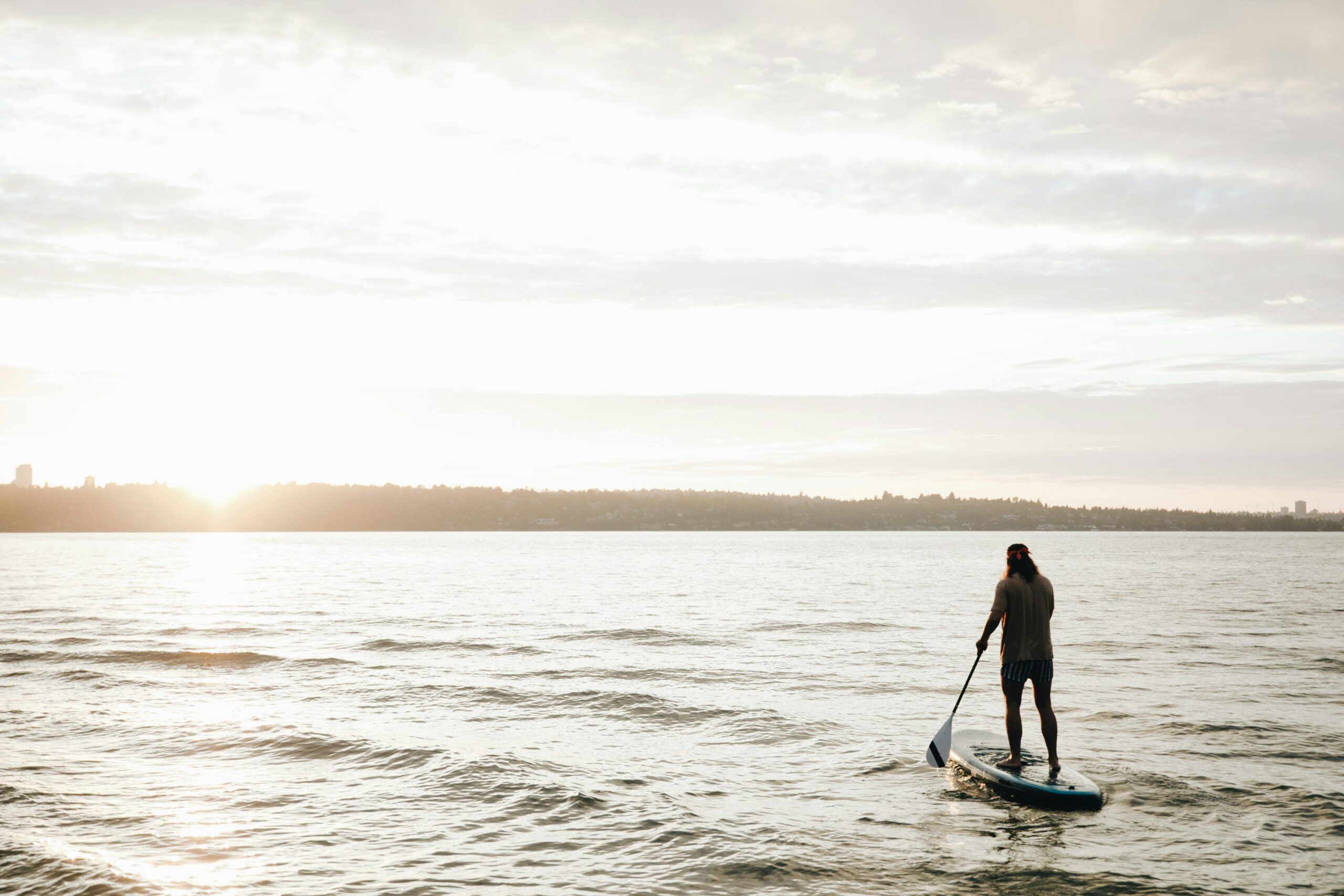 A person paddleboarding on the sea during a beautiful sunset, capturing a peaceful vacation moment.